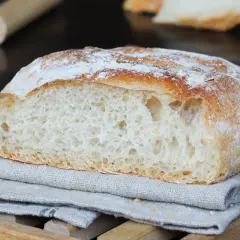 Pane fatto in casa con farina 00, tagliato a metà, mostra la mollica alveolata e la crosta dorata.