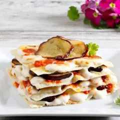 Strati di pane carasau con melanzane, mozzarella filante e pomodoro. Un'idea gustosa per le tue ricette.