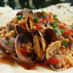 Fregola con arselle, uno dei piatti tipici della Sardegna, servita su pane carasau.