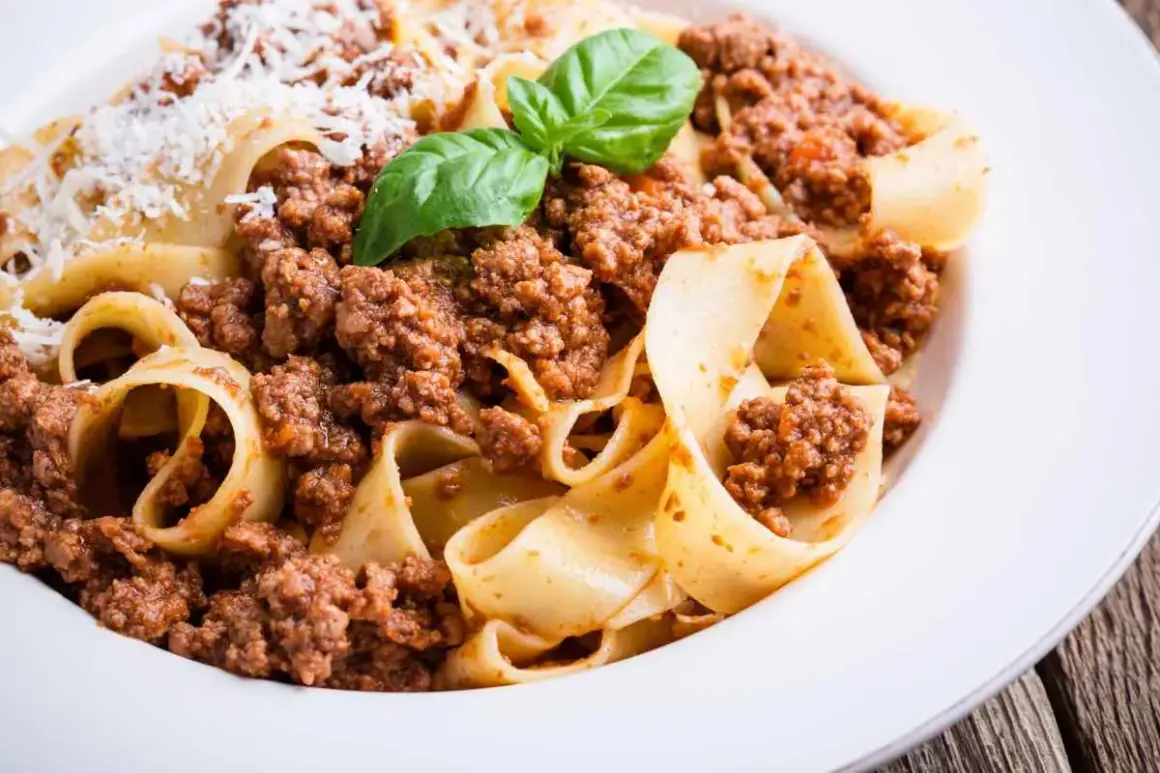 Pappardelle al ragù, un classico dei cibi tipici Emilia Romagna, con basilico fresco e parmigiano.