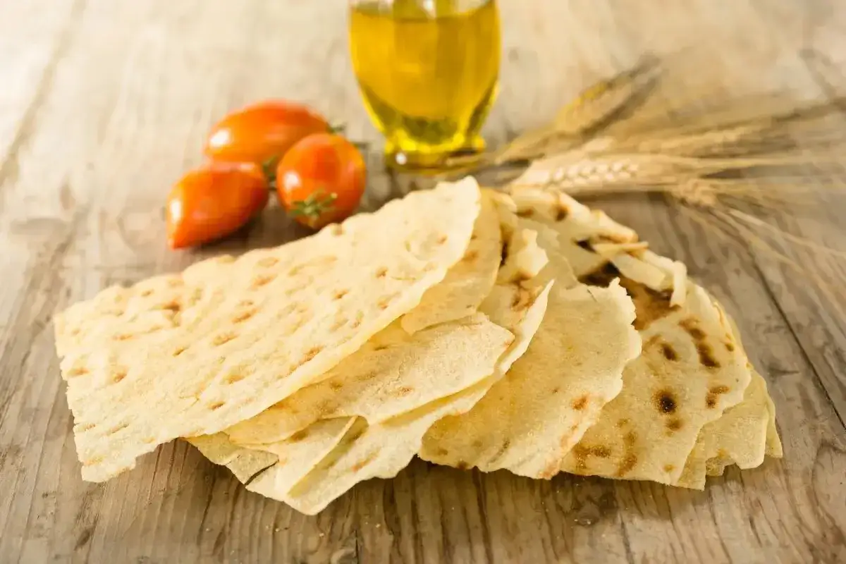 Pane carasau croccante, pomodorini e olio d'oliva, ingredienti perfetti per gustose ricette.