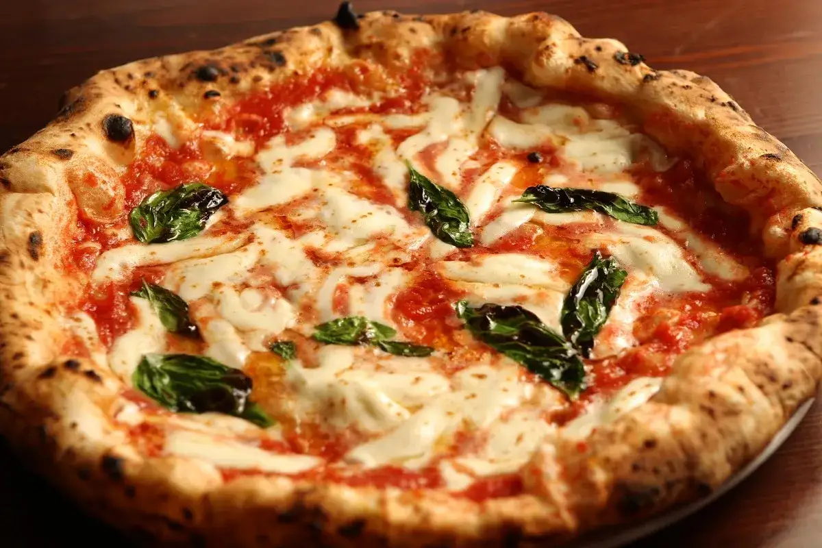 Pizza Margherita, uno dei piatti tipici della Campania, con pomodoro, mozzarella filante e basilico fresco.
