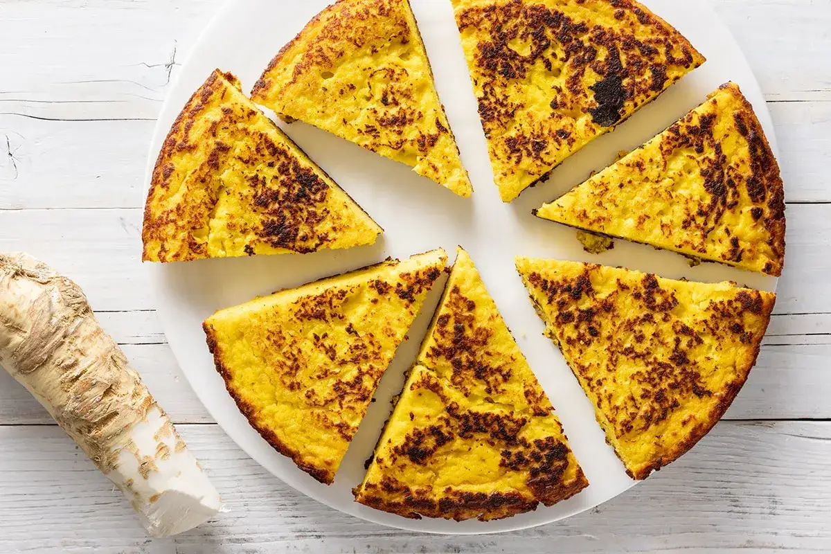 Fette di torta salata, uno dei piatti tipici Basilicata, con una radice di rafano a lato.